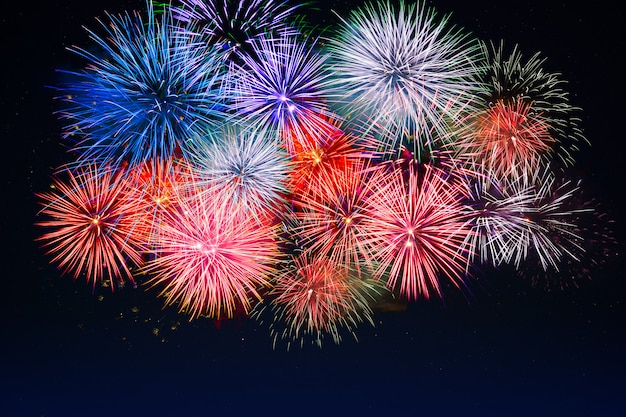 Increíbles fuegos artificiales rojos, dorados, azules sobre cielo nocturno