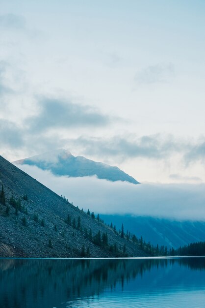 Increíbles siluetas de montañas y nubes bajas reflejadas en el lago de montaña.