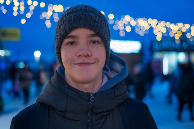 Incríveis momentos de férias, menino adolescente feliz posando na rua festiva da véspera de ano novo