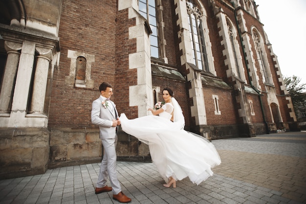 Incrível casal sorridente de casamento. noiva bonita e noivo elegante perto da igreja