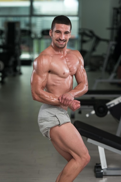 Incrível fisiculturista mostrando seus músculos e posando na academia