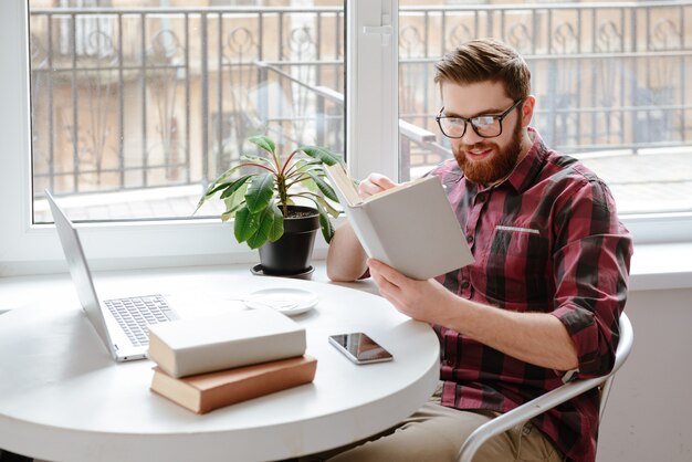 Incrível jovem barbudo estudante lendo livros.