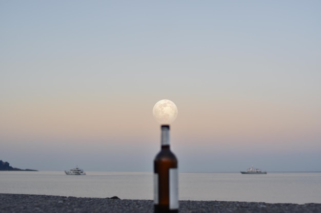 Incrível lua cheia sobre o mar e sobre garrafas abandonadas no cais