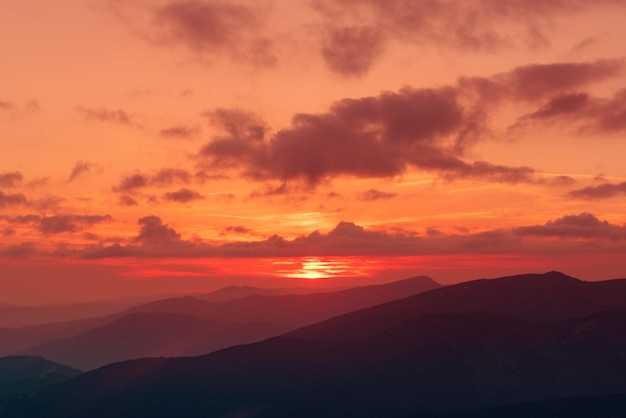 Incrível paisagem montanhosa com pôr do sol vívido colorido no fundo natural de viagens ao ar livre do céu brilhante