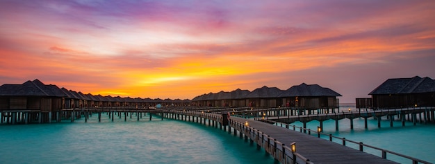 Incrível panorama do pôr do sol nas Maldivas. Seascape luxuoso das vilas do hotel resort, nuvens coloridas do céu