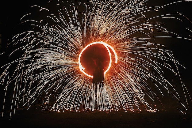 Incrível show de fogo à noite em festival ou festa de casamento Dançarinos de fogo girando fogo vermelho e homem fazendo malabarismo com faíscas brilhantes na noite show de fogo desempenho e entretenimento