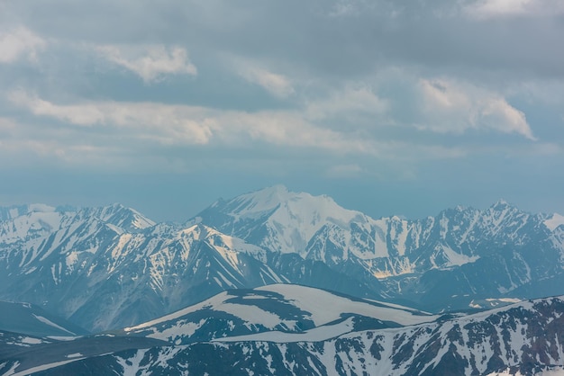 Incrível vista aérea sombria para o pico da montanha de neve alta na paisagem de montanha atmosférica nublada em alta altitude com nebulosidade cenário alpino com topo de montanha de neve no centro sob céu nublado