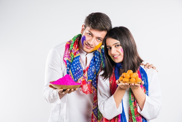 Inder feiern Holi mit süßem Laddu, Farben in Thali und Farbspritzer