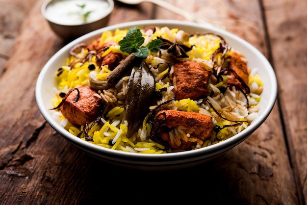 Indian Chicken Tikka Biriyani servido em uma tigela com iogurte. foco seletivo