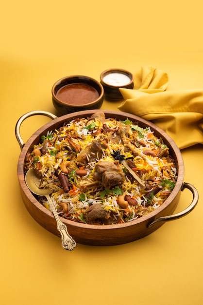 Indian Mutton Biryani preparado em arroz Basmati servido com molho de iogurte sobre fundo sombrio, Foco seletivo