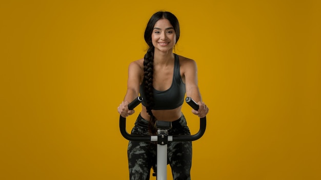 Indian slim feliz sonriente mujer deportiva chica atlética ciclismo flexión ciclismo montando en bicicleta estática