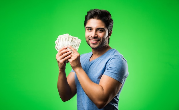 Indiano feliz com um leque de dinheiro, isolado contra uma tela verde cromada