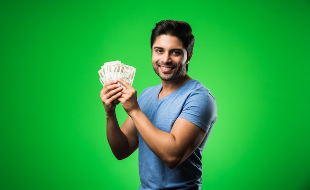 Indiano feliz com um leque de dinheiro, isolado contra uma tela verde cromada