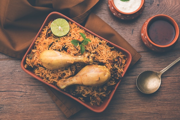 Indiano frango Biryani servido em uma tigela de terracota com iogurte sobre fundo branco. foco seletivo