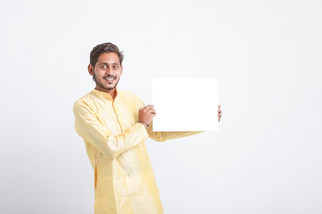 Foto indiano segurando uma lousa em pé sobre uma parede branca
