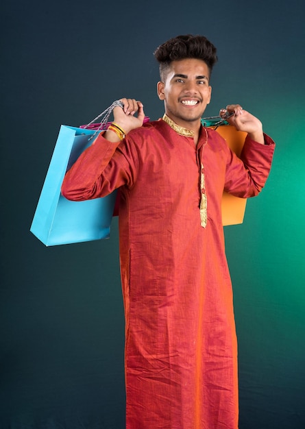 Foto indiano tradicional jovem homem bonito segurando e posando com sacos de compras em um fundo escuro