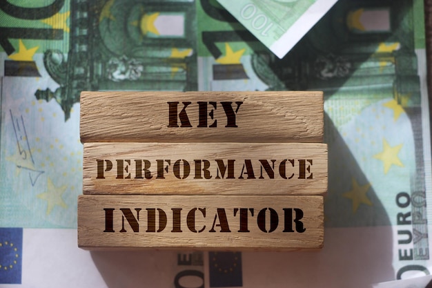 Indicador clave de rendimiento KPI escrito en bloques de madera frente a billetes de 100 euros Concepto de análisis empresarial