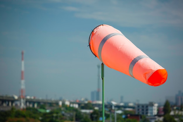 Indicador de windsock de vento no cone químico do tanque indicando direção e força do vento. Cata-vento voando horizontalmente (cata-vento) com céu de nuvem ao fundo.