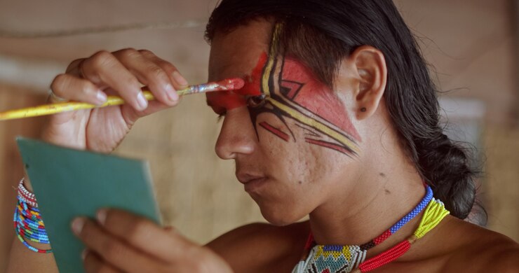 Foto índio da tribo pataxo usando espelho e pintando o rosto