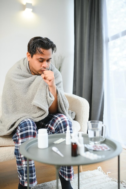 Foto un indio enfermo con cuadros se sienta solo temblando de frío un árabe enfermo se sienta en una silla sintiendo incomodidad tratando de calentarse