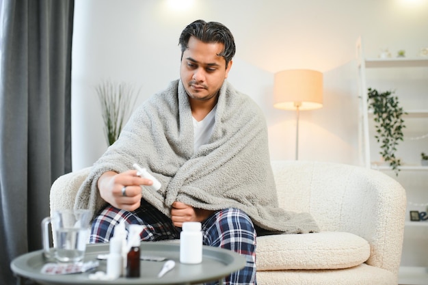 Un indio enfermo vestido a cuadros se sienta solo temblando de frío un árabe enfermo se sienta en una silla sintiendo incomodidad tratando de calentarse
