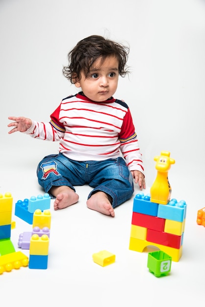 Índio fofo bebezinho ou criança brincando com brinquedos coloridos ou blocos sobre fundo branco,