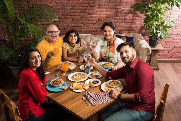 Indische Familie, die zu Hause am Esstisch isst oder im Restaurant zusammen isst