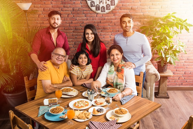 Indische Familie, die zu Hause am Esstisch isst oder im Restaurant zusammen isst