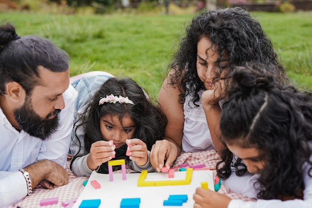 Indische Familie genießt den Tag zusammen im Stadtpark Hinduistische Eltern haben spielerische Zeit mit Kindern im Freien