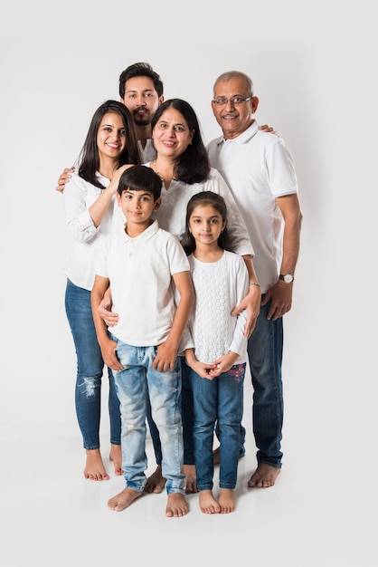 Indische Familienstellung lokalisiert über weißem Hintergrund. älteres und junges Paar mit Kindern, die weißes Top und blaue Jeans tragen. selektiver Fokus