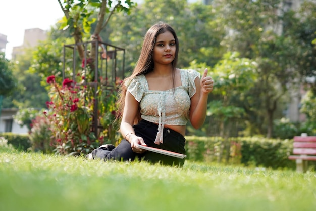 Indische Frau, die irgendwo beim Sitzen im Gras zeigt