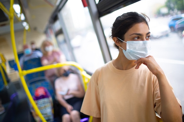 Indische Frau fährt in öffentlichen Verkehrsmitteln Bus oder Straßenbahn in medizinischer Gesichtsmaske