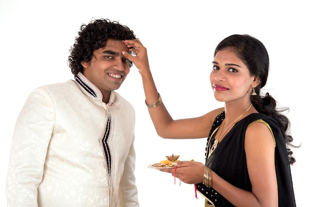 Foto indische junge schwester, die rakhi am handgelenk des bruders bindet, eine tradition auf dem raksha bandhan festival