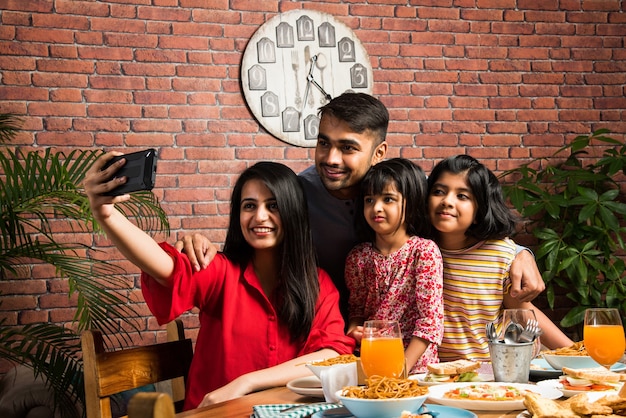 Indische junge vierköpfige Familie Essen am Esstisch zu Hause oder im Restaurant. Südasiatische Mutter, Vater und zwei Töchter beim gemeinsamen Essen