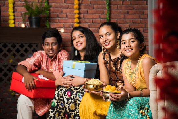 Indische kinder feiern diwali, deepawali, bhai dooj oder rakhi oder raksha bandhan mit blumenrangoli, geschenken, diya