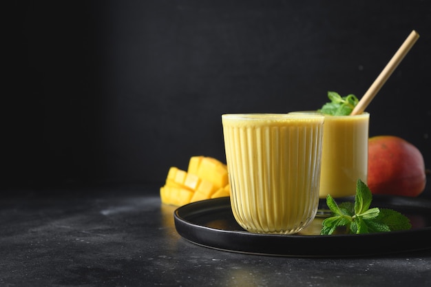 Indische Mango oder Kurkuma Lassi auf schwarzem Hintergrund