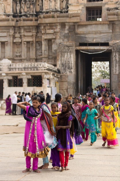 Indische Menschen in farbenfroher Kleidung betreten den Tempel in der antiken Stadt Hampi, die zum UNESCO-Weltkulturerbe gehört