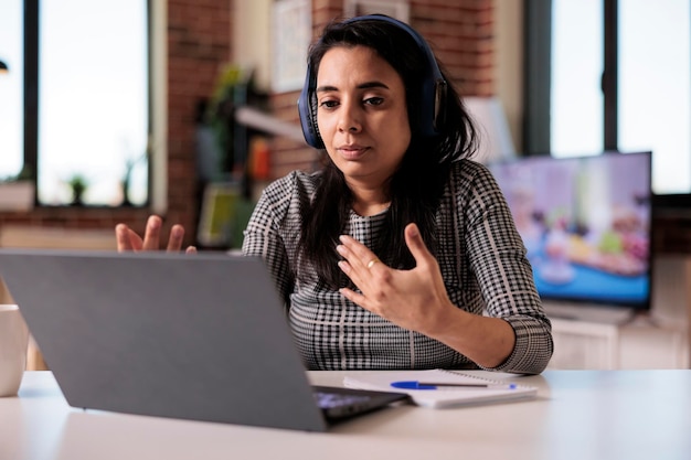 Indische Person nimmt an Videoanrufkonferenz auf Laptop teil und spricht mit Leuten bei Online-Geschäftstreffen mit Webcam. Verwenden von Remote-Videokonferenzanrufen, um zu Hause über Telekommunikation zu chatten.