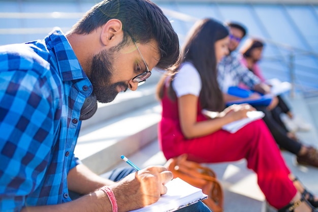 Indische Studenten halten Abstand und machen Hausaufgaben im Freien