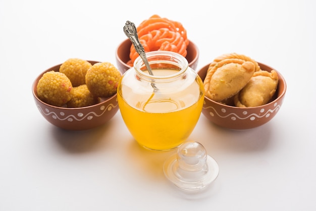 Indische Süßigkeiten Gujiya, Motichoor Laddu und Jalebi und geklärte Butter oder indisches Desi Ghee in einem Glas, selektiver Fokus