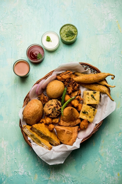 Indische Tee-Snacks in der Gruppe umfassen Veg Samosa, Kachori, Kachaudi, Aloo Bonda, Khaman Dhokla, Brot, Zwiebeln, Chili und Moong Pakora, Pakoda, Bhaji, Bhajji, Bhajiya, Bajji mit Saucen