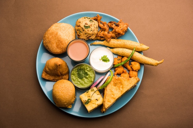 Indische Tee-Snacks in der Gruppe umfassen Veg Samosa, Kachori, Kachaudi, Aloo Bonda, Khaman Dhokla, Brot, Zwiebeln, Chili und Moong Pakora, Pakoda, Bhaji, Bhajji, Bhajiya, Bajji mit Saucen