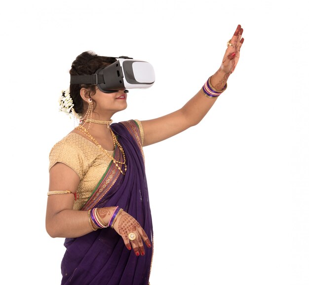 Indische traditionelle junge Frau im Saree, der durch VR-Gerät schaut