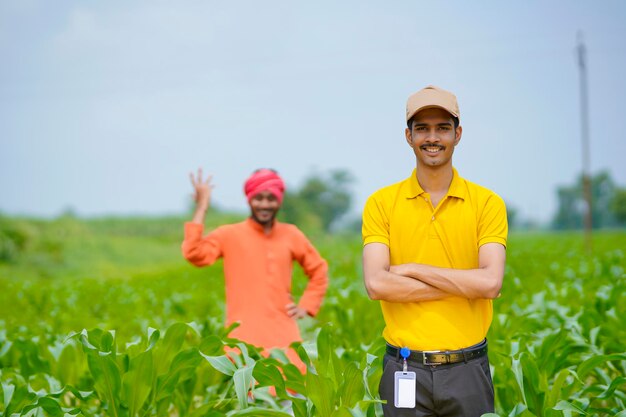 Indischer Agronom mit Landwirt am grünen Landwirtschaftsfeld.