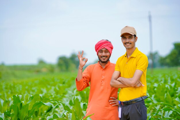 Indischer Agronom mit Landwirt am grünen Landwirtschaftsfeld.