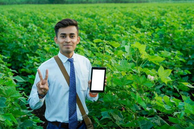 Foto indischer agronom oder banker mit tablet oder telefon auf dem landwirtschaftsfeld