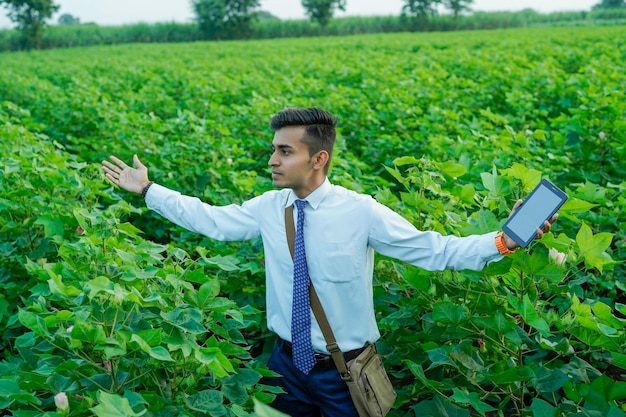 Foto indischer agronom oder banker mit tablet oder telefon auf dem landwirtschaftsfeld
