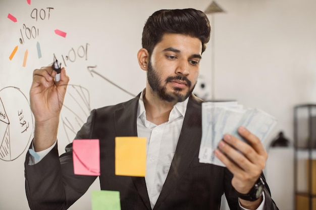 Indischer Arbeitgeber schreibt an Bord und hält Bargeld bei der Arbeit bereit