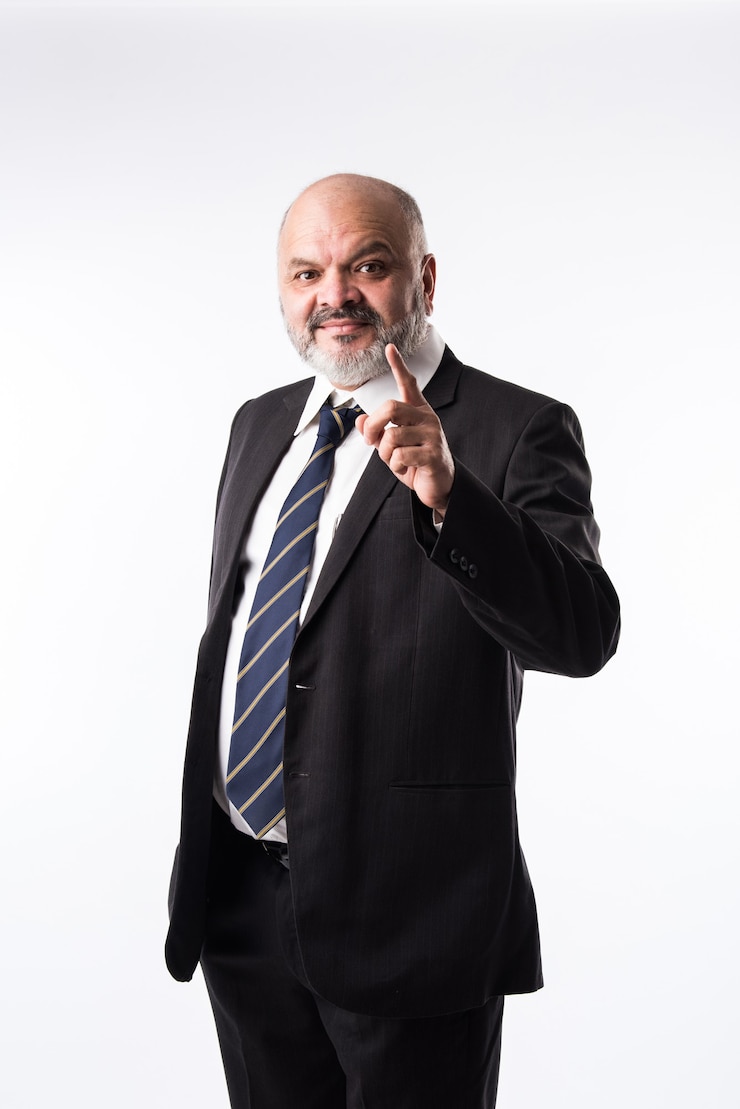 Foto indischer asiatischer geschäftsmann mittleren alters mit bart, der eleganten schwarzen anzug trägt und mit hand und finger zeigt. präsentation von produkten, dienstleistungen oder kopienraum