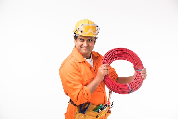 Indischer asiatischer gutaussehender Elektriker oder Ingenieur in Aktion mit gelbem Sicherheitshut isoliert